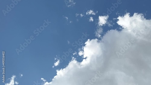 Timelapse of a fluffy cumulus cloud formation with sunlight, clear blue sky and shade, horizontal video photo