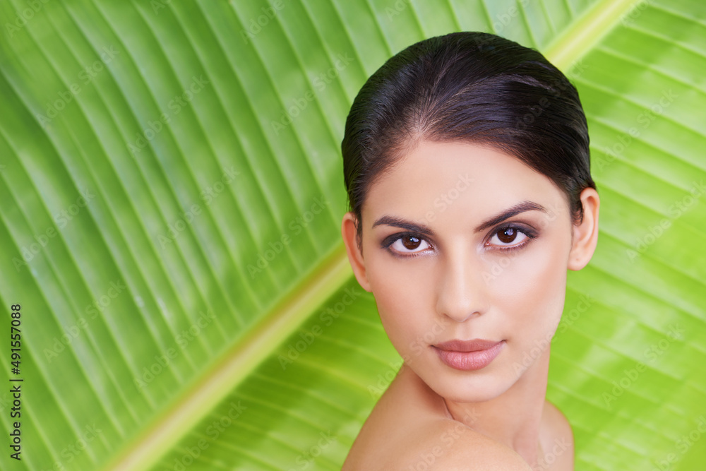 Shes all natural beauty. Studio portrait of a beautiful young woman posing in front of a leaf. Shes all natural beauty. Studio portrait of a beautiful young woman posing in front of a leaf.
