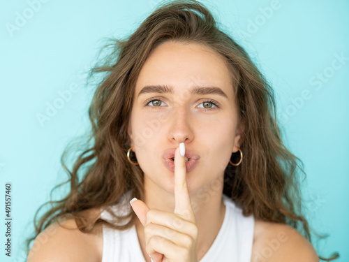 Shush finger. Female portrait. Mute expression. Pretty beautiful woman showing gesture for keeping secret isolated blue.