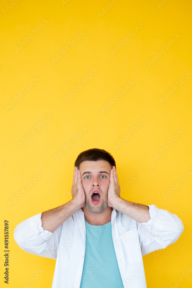 Shocked news. Amazed man. Disbelief expression. Surprised guy with opened mouth holding hands on face isolated yellow. Shocked news. Amazed man. Disbelief expression. Surprised guy with opened mouth holding hands on face isolated yellow.
