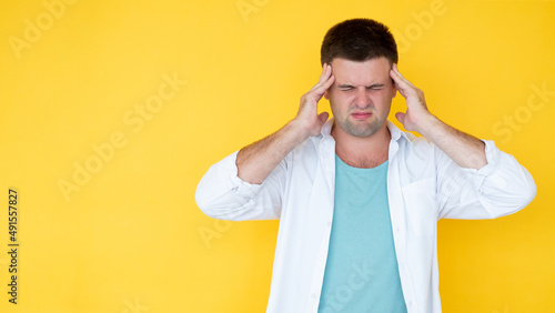 Headache suffer. Sick man. Healthy problem. Desperate overload guy holding head with hands on temples isolated yellow copy space.