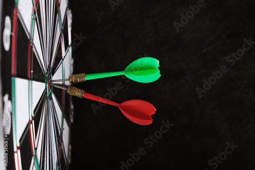 Two darts are stuck in the center of dartboard.Achieving goals in business and in life.