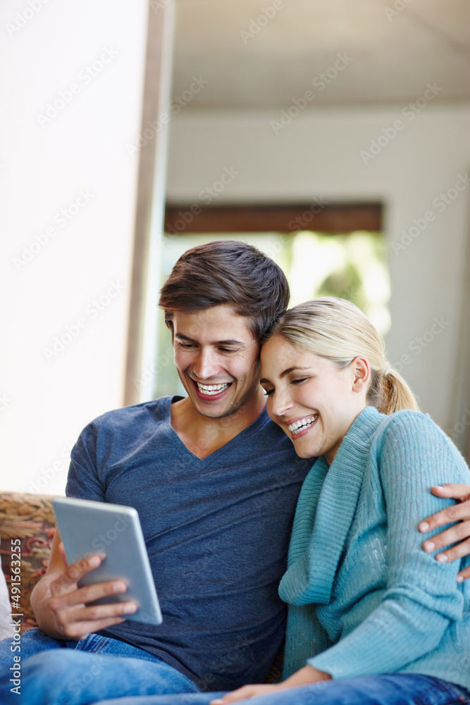 Watching something wacky on the web. Shot of a happy young couple using a digital tablet together on the sofa at home.