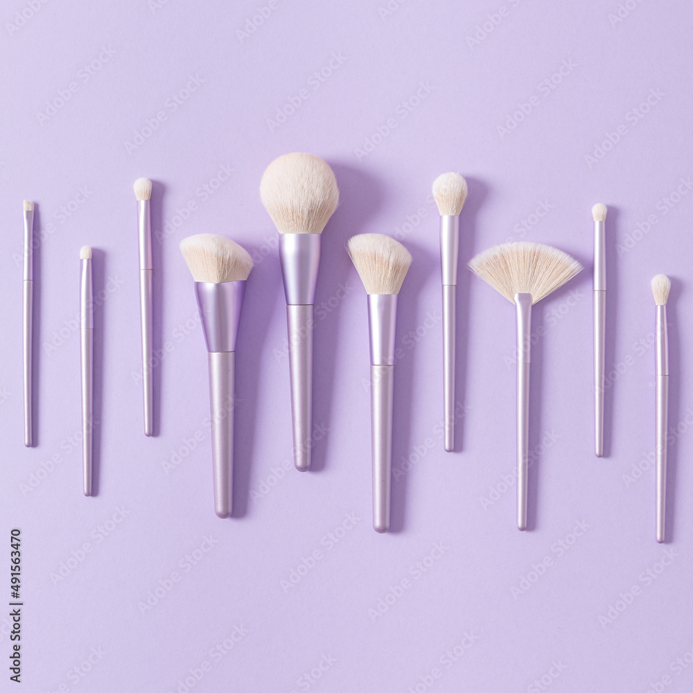 Set of different make up brushes, violet make up tools on violet background. Professional make up brushes for visagist. Cosmetic composition. Magazine, cosmetics store, social media. Square Set of different make up brushes, violet make up tools on violet background. Professional make up brushes for visagist. Cosmetic composition. Magazine, cosmetics store, social media. Square
