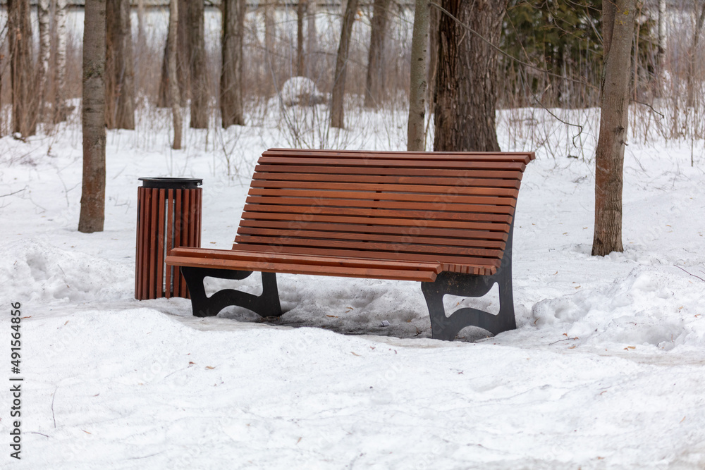 Wooden bench with an urn on the snow