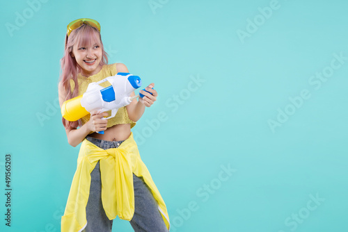 Canvas Print Happy Asian beautiful girl holding a water gun on pastel green mint color background