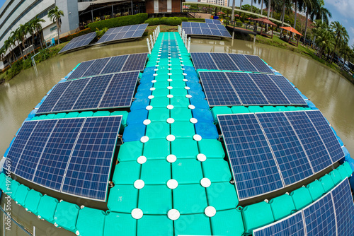 Platform of Plastic Floating Solar Cells  Panels on the water against blue sky inside public park in the city centre.
