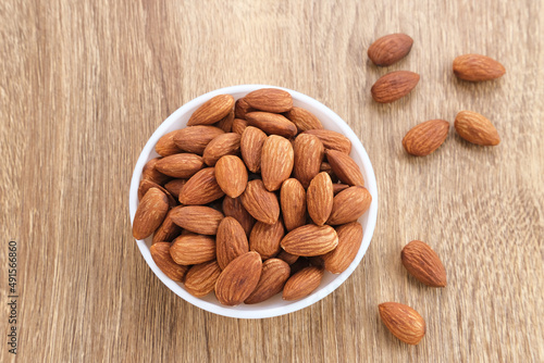 Almonds in bowl on wooden table.  Close up. Selected focus
 photo