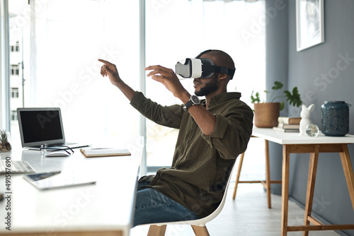 Tomorrows world is created today. Shot of a young businessman using a virtual reality headset in a modern office.