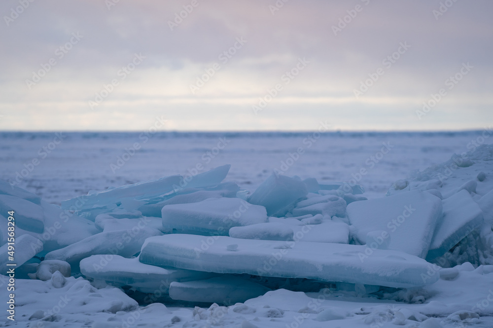 Obraz premium Blue Ice Chunks on Lake Michigan - Frozen Lake with snow, beautiful colorful sky, and clouds in the background