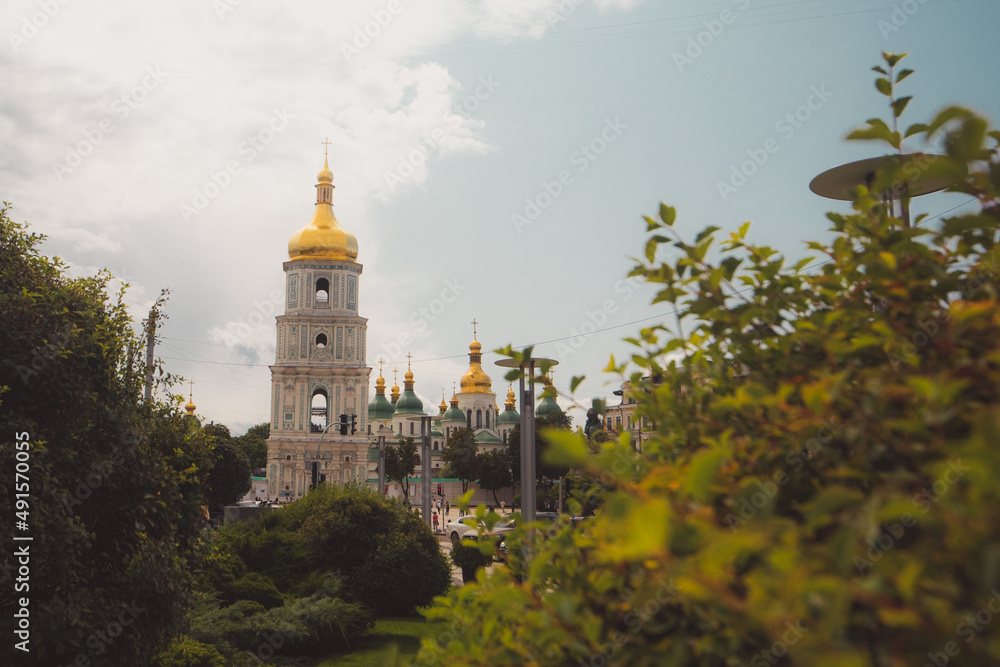 Bell tower of Sant Sophia cathedral in Kiev, Ukraine, viewed from distance through the bushes on a sunny day in summer Bell tower of Sant Sophia cathedral in Kiev, Ukraine, viewed from distance through the bushes on a sunny day in summer