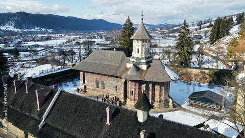 Aerial drone view of Moldovita Monastery in Vatra Moldovitei in winter, Romania. Snow, yard with tourists, residential buildings around photo