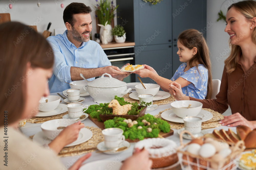 Family sharing plate with egg during easter dinner