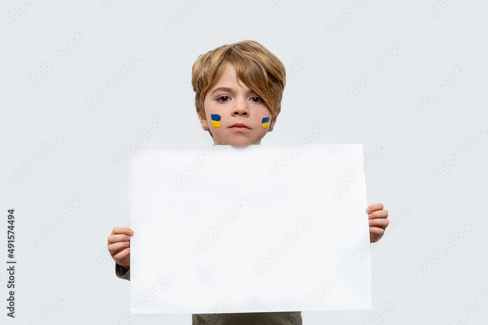 Sign of Ukrainian flag on child cheek. Ukrainian geopolitics globe crisis. Close up kids face. Child holds poster with copy space. Isolated on white background. International children day Sign of Ukrainian flag on child cheek. Ukrainian geopolitics globe crisis. Close up kids face. Child holds poster with copy space. Isolated on white background. International children day