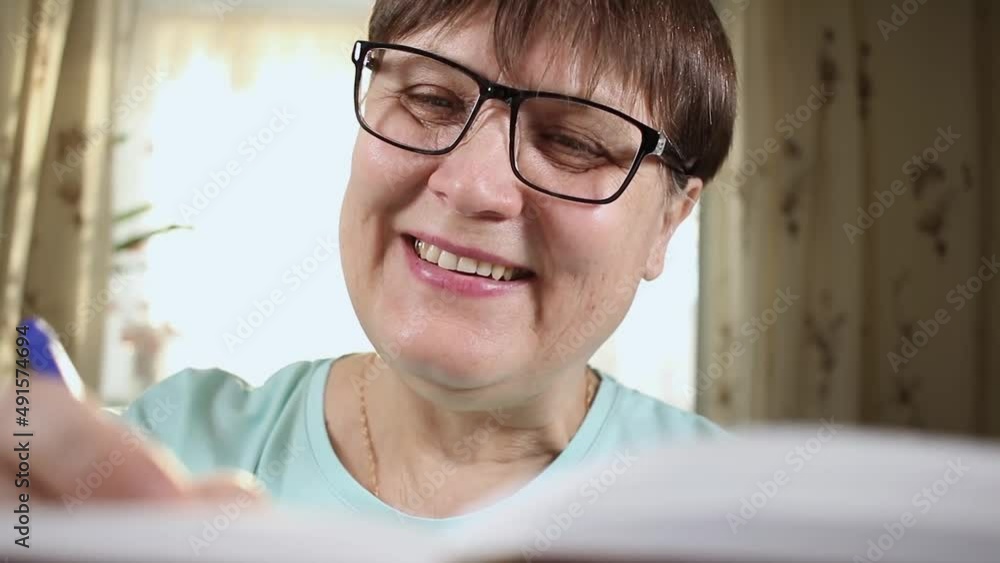 An elderly woman writes something in a notebook. An elderly woman writes something in a notebook.
