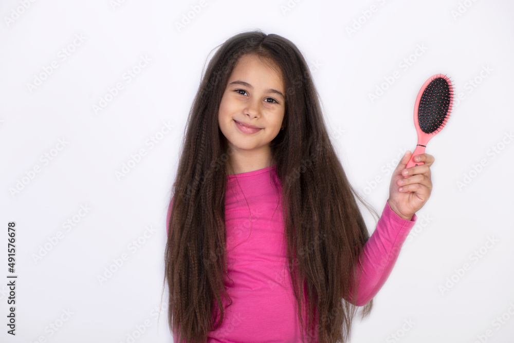 Girl long curly hair grey interior background. Child curly hairstyle hold hairbrush or comb. Apply oil before combing hair. Healthy hair. Conditioner or mask organic oil comb hair. Beauty salon tips Girl long curly hair grey interior background. Child curly hairstyle hold hairbrush or comb. Apply oil before combing hair. Healthy hair. Conditioner or mask organic oil comb hair. Beauty salon tips