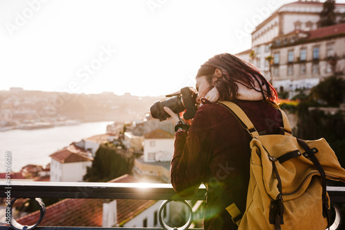 woman in Porto bridge taking pictures with camera at sunset. Tourism in city Europe. travel