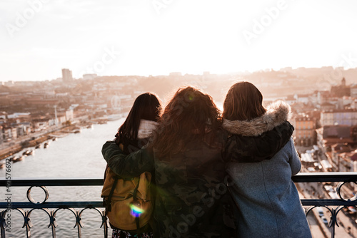 Three happy friends Porto bridge sightseeing at sunset. Travel, friendship and Lifestyle photo