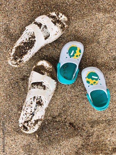 Family picture - sand sandals of mom and a kid at vacation on the sea shore, sandy beach