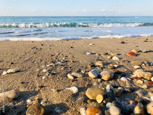 Beach with waves and little stones at the shore of the sea. Holiday and vacation at the sea