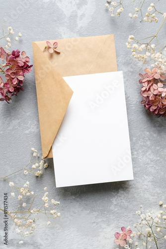 Wedding invitation or blank greeting card mockup with envelope and flowers decorations. © nikavera