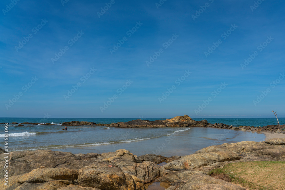 Rocks at the Bentota beach, background blue sky Indian Ocean, Sri Lanka