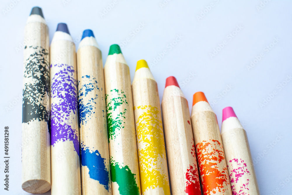 Several pencils are lying on the white piece of paper. The rainbow which made of pencils. Several pencils are lying on the white piece of paper. The rainbow which made of pencils.
