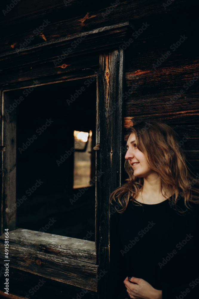 beautiful Ukrainian girl in black clothes near the old wooden house. The war in Ukraine. Portrait of a woman on a dark wooden background. Old abandoned wooden house. Old wooden window frame beautiful Ukrainian girl in black clothes near the old wooden house. The war in Ukraine. Portrait of a woman on a dark wooden background. Old abandoned wooden house. Old wooden window frame