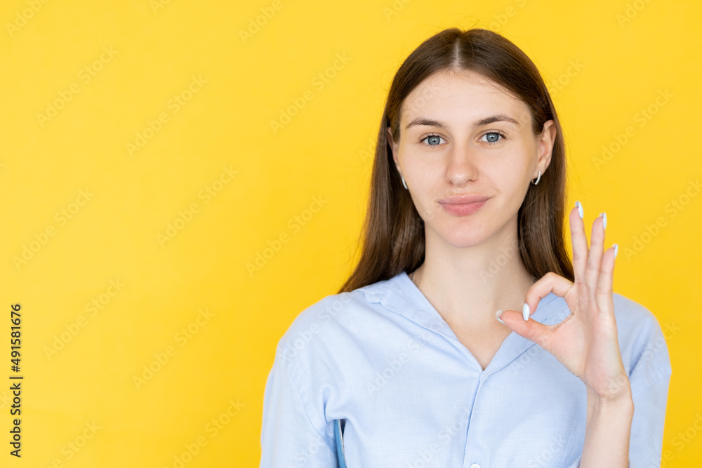 Positive answer. Smiling woman. Ok gesture. Pretty confident lady in casual shirt showing approving sign isolated yellow copy space. Positive answer. Smiling woman. Ok gesture. Pretty confident lady in casual shirt showing approving sign isolated yellow copy space.
