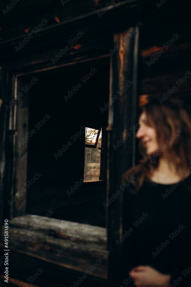 beautiful Ukrainian girl in black clothes near the old wooden house. The war in Ukraine. Portrait of a woman on a dark wooden background. Old abandoned wooden house. Old wooden window frame beautiful Ukrainian girl in black clothes near the old wooden house. The war in Ukraine. Portrait of a woman on a dark wooden background. Old abandoned wooden house. Old wooden window frame