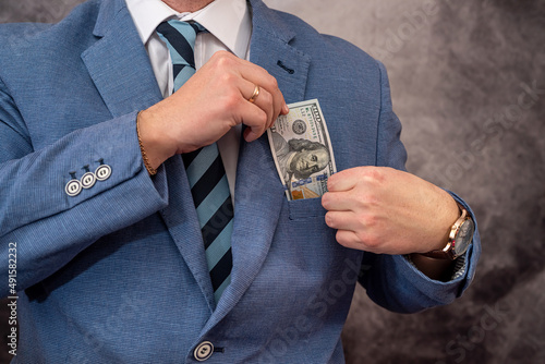 Young man in suit putting dollar bills in his pocket