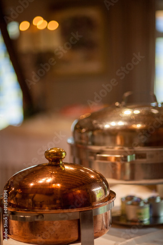 Old copper casserole with lid and brass handles in copper flower pot on a normal background. Food photography props. High quality photo