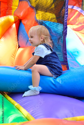 Obraz na plátně Little girl jumping on an inflatable attraction