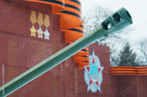 Fragment of the monument to the heroes of the Second World War. The barrel of an artillery gun. May 9 is Victory Day in the Great Patriotic War. St. George ribbon and orders in blur