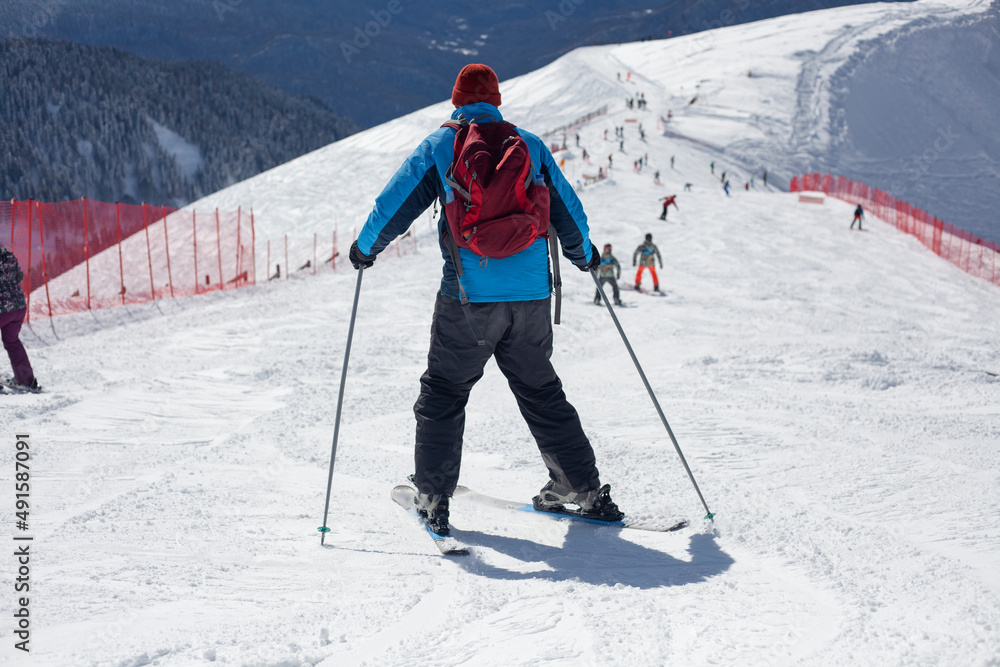 A skier rides on a snowy slope. Active rest in the winter. The athlete is preparing for the descent. Mountain ski resort. Outdoor activities on a winter vacation. A skier rides on a snowy slope. Active rest in the winter. The athlete is preparing for the descent. Mountain ski resort. Outdoor activities on a winter vacation.