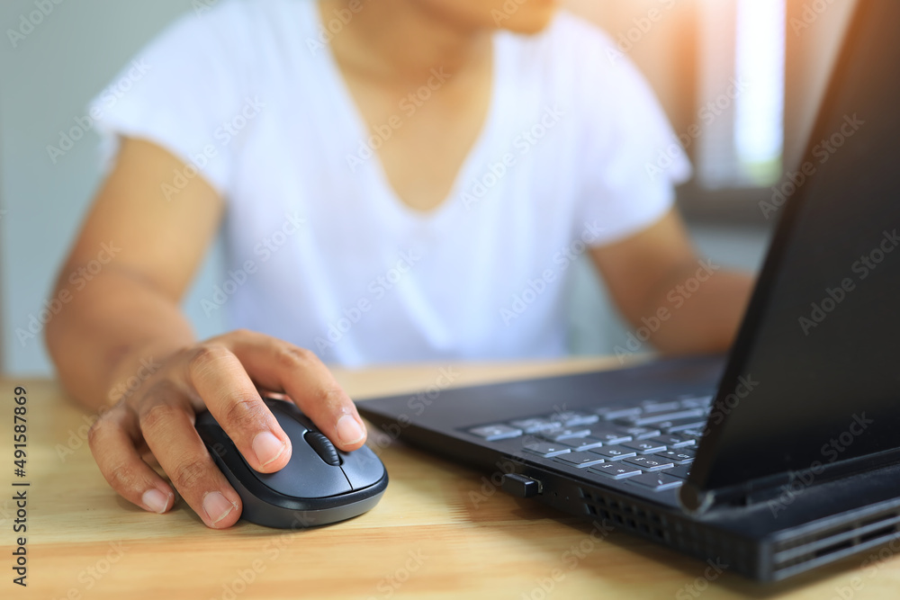 A man wearing a white short-sleeved shirt in comfortable clothes is using a computer at his home office during the COVID-19 pandemic. Work from home concept. A man wearing a white short-sleeved shirt in comfortable clothes is using a computer at his home office during the COVID-19 pandemic. Work from home concept.