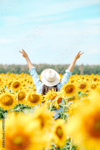 Young beautiful blonde woman standing in sunflower field.
 