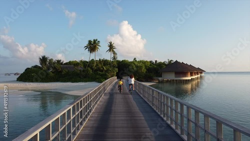 Mother and son riding their bikes throw a bridge on a Maldive Islands