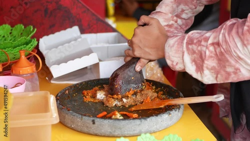 Making ayam geprek, popular fusion dish of smashed southern fried chicken with topping of red chili relish. Ayam geprek is one of the favorite foods among young people of Indonesia. photo
