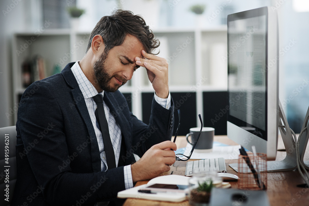The pressures of the day are driving him insane. Shot of a young businessman looking stressed out while working in an office. The pressures of the day are driving him insane. Shot of a young businessman looking stressed out while working in an office.