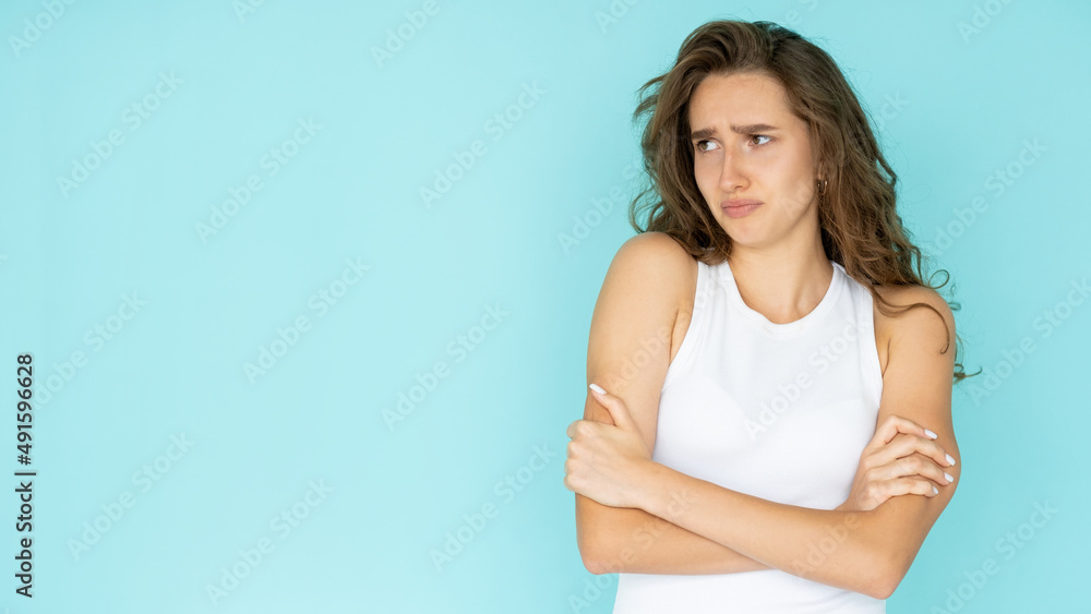 Displeased situation. Offended woman. Unhappy feelings. Upset pretty lady in white dress crossing hands on chest isolated blue looking copy space. Displeased situation. Offended woman. Unhappy feelings. Upset pretty lady in white dress crossing hands on chest isolated blue looking copy space.