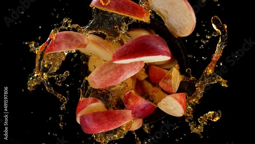 Super slow motion shot of rotating exploded red apple cuts and splashing Juice on black at 1000fps. photo