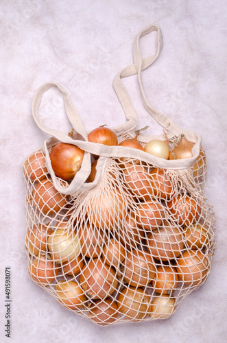 Fresh yellow onions in a knitted bag