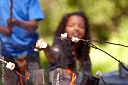 The perfect snack to enjoy with friends. Kids roasting marshmallows on an open fire.