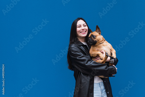 Pleased laughing young asian woman look embraces French Bulldog  expresses true love