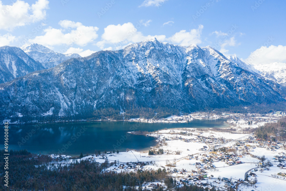 Aerial view. Winter Alpine lake Grundlsee. Embedded in the wonderful mountain massif of the Dead Mountains. Clear cold landscape with blue sky and cumulus clouds