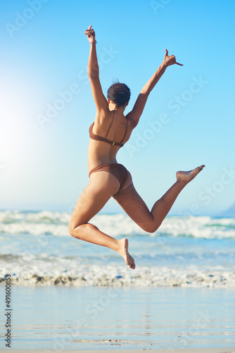 Nothing compares to the joy of a beach day. Rearview shot of a young woman standing on the beach.