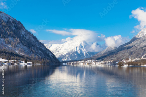 Fototapeta Naklejka Na Ścianę i Meble -  Winter alpine lake Grundlsee. Embedded in the wonderful mountain massif of the Dead Mountains. Clear cold landscape with blue sky and cumulus clouds. Ausserland, Styria, Austria.