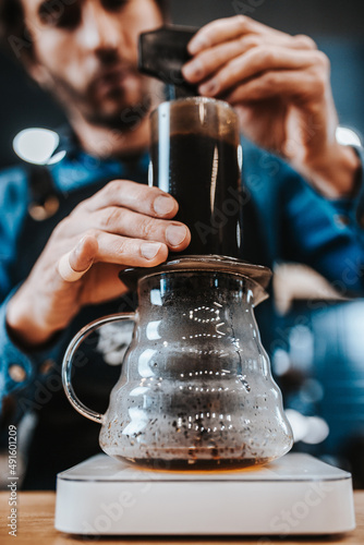 A man prepares drip coffee with a manual press - rich aromatic black coffee for vigor