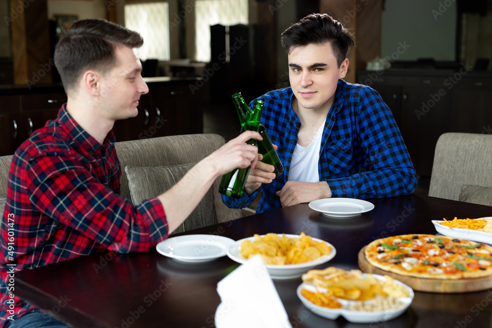 Young men drinking beer and talking in cafe